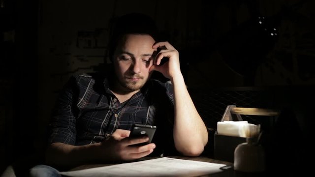 Hipster man using smartphone in cafe in the night