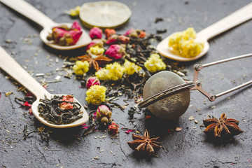 Tea herbs and spoons on grey background