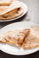 Crispy Quesadilla with Chicken and Sauce on white plate on dark wooden background vertical shot