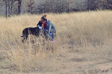 Girl kissing dog in rustic natural field of grass.  Love and affection with man's best friend and person.