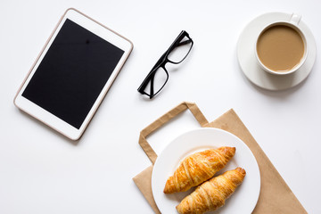 Business lunch with croissant and tablet on white table top view