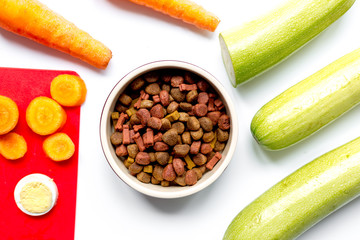 Dry dogfood with sliced vegetables on table background top view