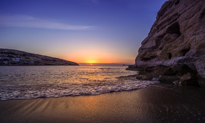 Panorama of Matala beach at sunset with the caves on the rocks that were used as a roman cemetery and at the decade of 70's were living hippies from all over the world, Crete, Greece