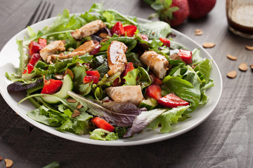 Strawberry Orange Honey Balsamic Salad on spring baby greens and spinach on a dark wooden background