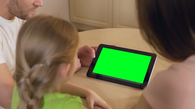 Happy family using application on tablet pc with pre-keyed green touchscreen