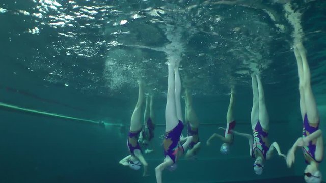 Synchronized swimming, team training, underwater view.
