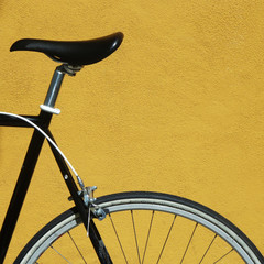Fototapeta na wymiar Close up of a black bicycle against a yellow background