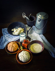 home made cheese over a rustic wooden table with its ingredients, milk, salt, paprika, curd and an old milk churn