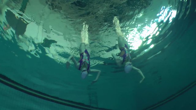 Synchronized swimming, two girls training, underwater.
