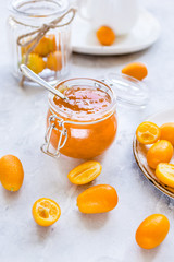 kumquat on plate and jam in jar at gray background