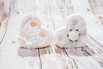 Two white hearts on wooden background. One heart with the word Love