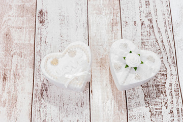 Two white hearts on wooden background. One heart with the word Love