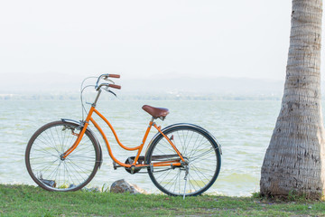 Fototapeta na wymiar Orange bicycle with the backdrop of the mountains and the sea with warm sunshine.