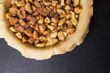 Raw homemade apple pie with cinnamon and walnuts, closeup