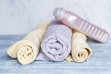 Fototapeta na wymiar housekeeping set with towels and plastic bottles on laundry background