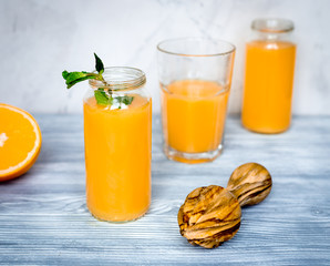 healthy orange cocktail with mint leaves in bottle on kitchen background
