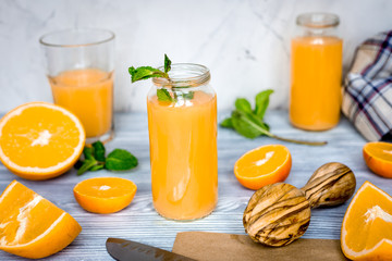healthy orange cocktail with mint leaves in bottle on kitchen background