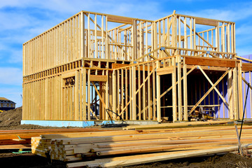 Two story wood frame residential building under construction with material in foreground.
