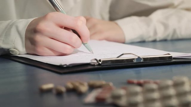 doctor's hand writing a prescription on a Rx blank form. Pharmaceutical, medical, medicament background