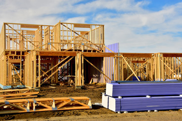 Two story wood frame residential building under construction with material in foreground.