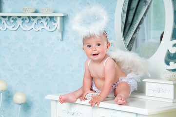 Little angel smiling and sitting on the dressing table