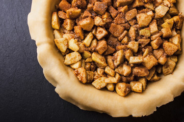 Raw homemade apple pie with cinnamon and walnuts, closeup