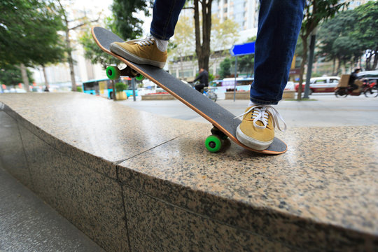 young skateboarder legs riding skateboard at city skatepark