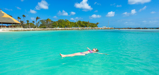 Woman floating on a back in the beautiful sea. Aruba island - obrazy, fototapety, plakaty