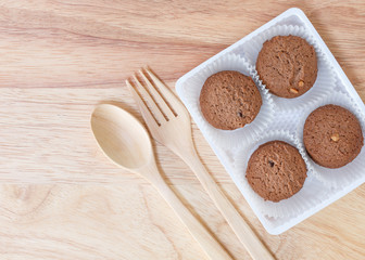 Cookies chocolate in plastic box and spoon fork on wood background