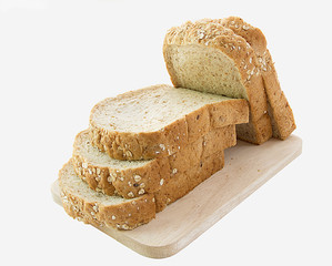 whole grain bread and slices on wooden cutting board and on white background