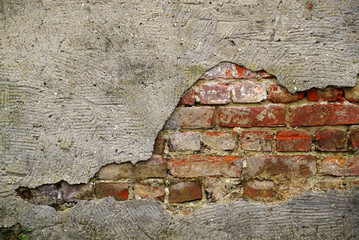 A whole in the concrete roughcast that reveals a brick wall. © Camille