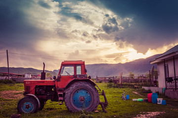 Fototapeta premium Very old tractor on the grass field and dramatic sky