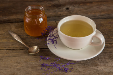 Cup of tea with honey in jar on the wooden table