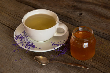 Cup of tea with honey in jar on the wooden table