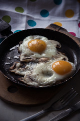Two fried eggs with mushrooms in a pan