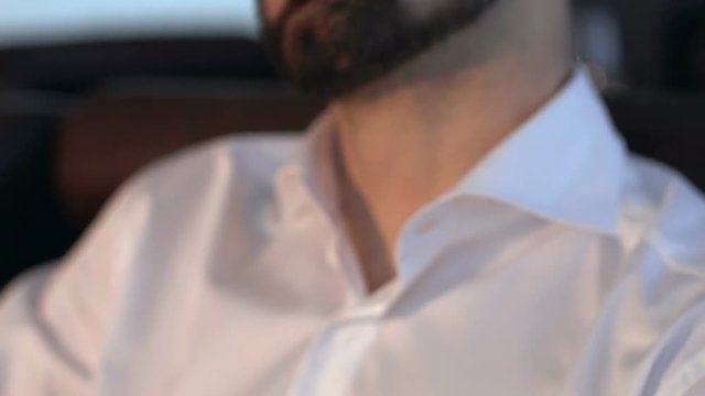 Attractive pensive young man looking to the side stroking his beard.