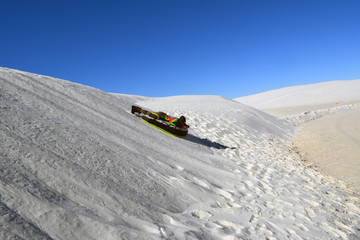 Dune Tubing/Teenager sliding down sand dune.