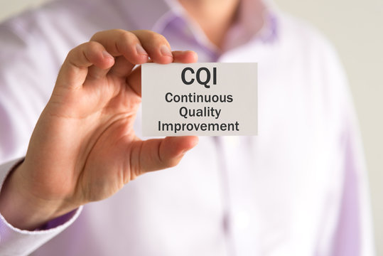 Businessman holding a card with text CQI Continuous Quality Improvement