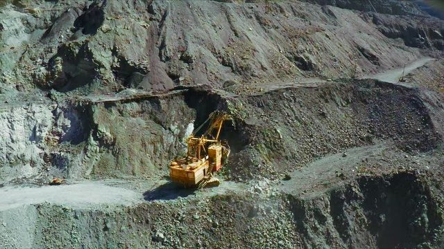 Aerial. An excavator is extracting minerals in an open pit