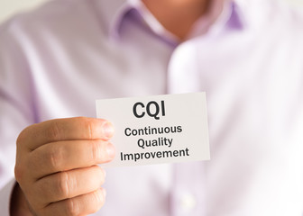 Businessman holding a card with text CQI Continuous Quality Improvement