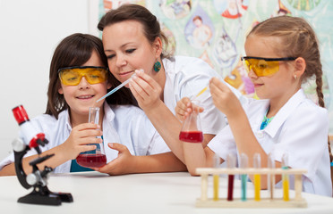 Teacher sitting at the desk with her young students
