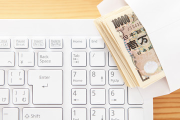 キーボードと封筒に入ったお金