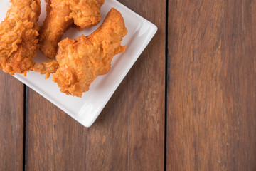 Fried chicken on the wooden background.