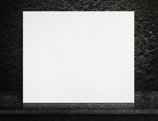 Blank paper white poster on black marble table top with leg at blur black rough stone background,Mock up for adding your design or text