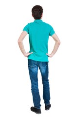 Back view of man in jeans. Standing young guy. Rear view people collection.  backside view of person.  Isolated over white background. A guy in a T-shirt is stylish aquamarine hands on hips.