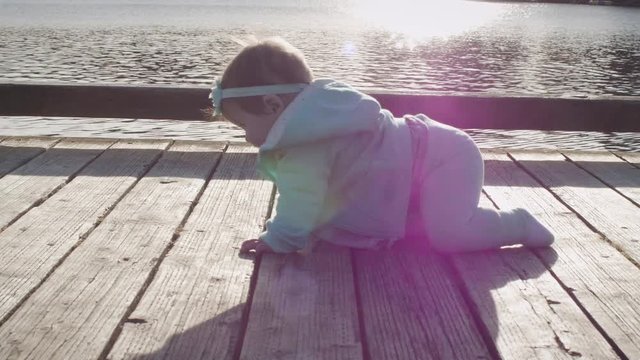 Baby Girl Learning to Crawl on Wood Dock by Lake with Flat Profile Vintage Lens Sun Flare