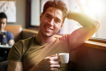 Attractive Young Man Eating Breakfast, Drinking Coffee and Smiling to the Camera