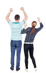 Obraz premium Back view of joyful couple celebrating victory hands up.