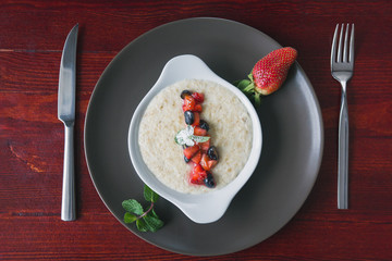 Bowl of oatmeal porridge with fruits and greens, hot and healthy food for Breakfast, top view