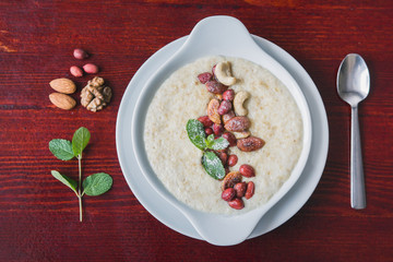 Bowl of oatmeal porridge with nuts and greens, hot and healthy food for Breakfast, top view